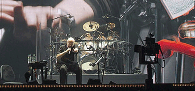 Musicians performing live on stage in front of a giant screen